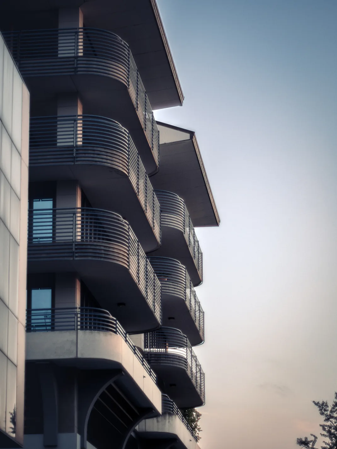 Fachada de edifício residencial com sacadas em curva iluminadas pelo entardecer